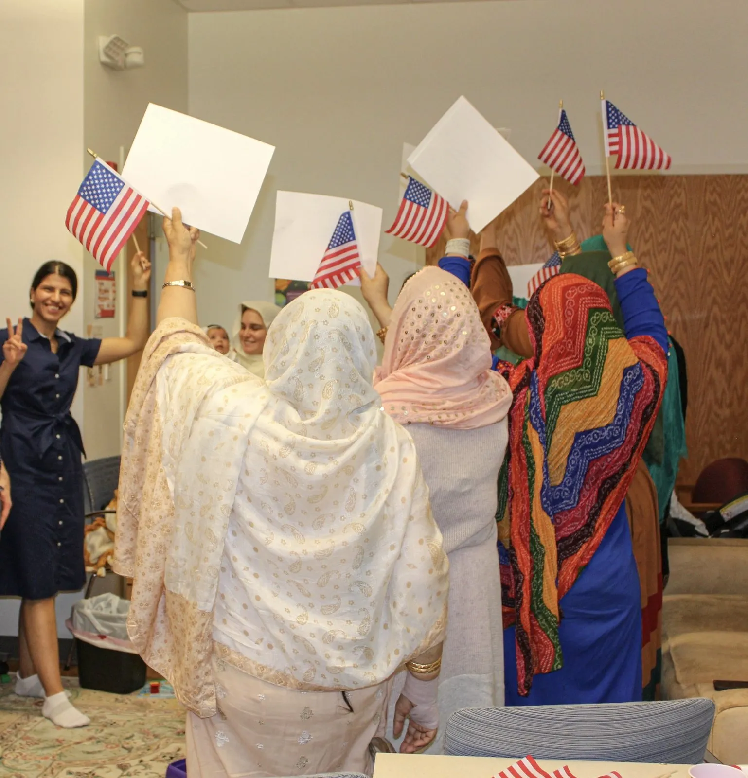 Negar with her adult ESOL class, students holding small U.S. flags